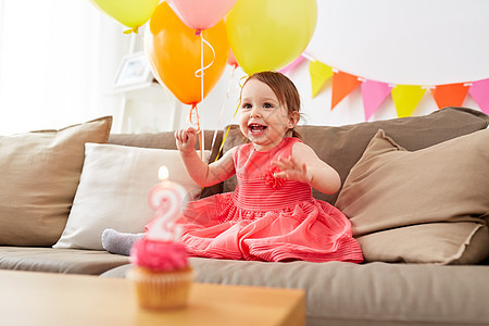 童,假期人的快乐的女婴家里的生日聚会上,气球,花环纸杯蛋糕与蜡烛快乐的女婴家里的生日聚会上图片
