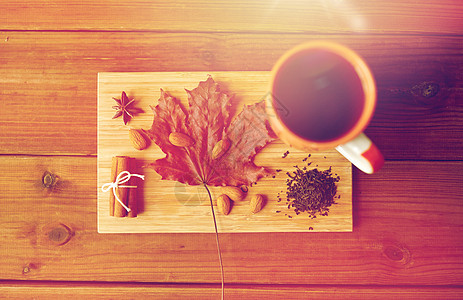 秋天季节的杯茶,枫叶杏仁木板上杯茶,枫叶杏仁木板上图片
