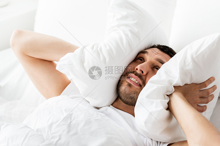 人们,睡觉时间休息的男人躺床上,枕头家里被噪音所困扰男人躺床上,枕头上噪音图片