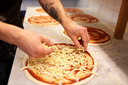 食物烹饪,烹饪人的厨师包师的手添加烤奶酪比萨饼店比萨店把磨碎的奶酪加比萨饼里饭图片