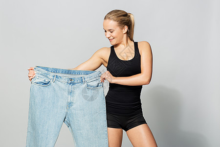 饮食,减肥人的轻的苗条运动妇女与超大裤轻的苗条运动女人,穿着超大的裤子图片