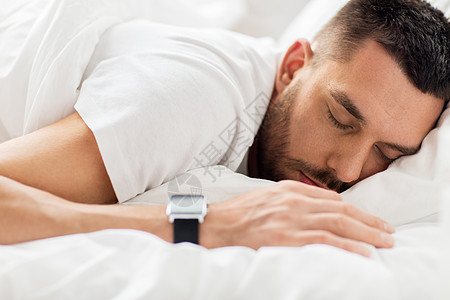 人,睡觉时间休息的与智能手表床上睡觉的人床上睡觉的智能手表的男人图片