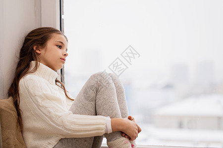 童,悲伤人的悲伤的美丽女孩穿着毛衣坐家里的窗台上冬天冬天,悲伤的女孩坐家里的窗户上图片
