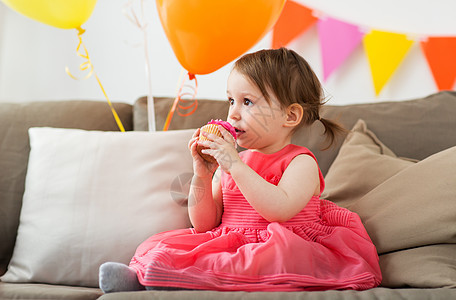 童,人庆祝快乐的女婴家里的生日聚会上吃纸杯蛋糕生日派上快乐的女婴吃纸杯蛋糕图片