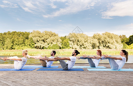 健身,运动,瑜伽健康的生活方式群人户外的垫子上半船姿势河流湖泊泊位人们半船式户外瑜伽图片