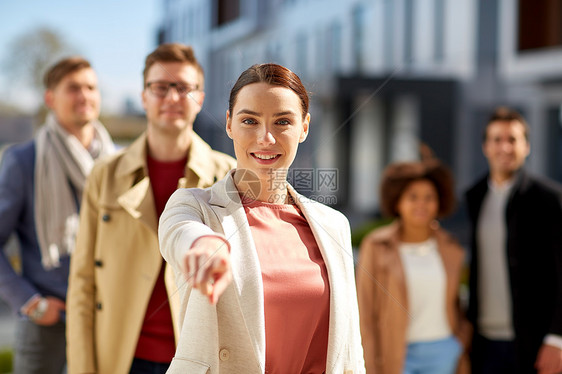 商业,选择企业快乐的微笑的女人指着你与国际集的人城市街道快乐微笑的女人指着你图片