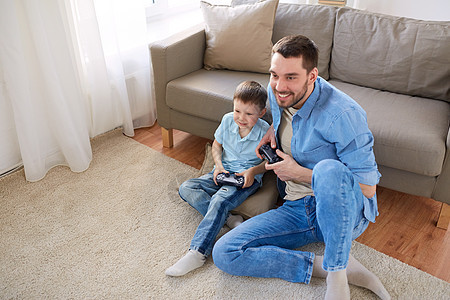 家庭,父亲人的快乐的父亲小儿子与游戏垫家里玩电子游戏父子家里玩电子游戏背景图片