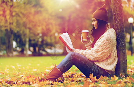 季节,文学,教育人的轻的女人阅读书籍喝咖啡纸杯秋季公园带着书秋天公园喝咖啡的女人图片