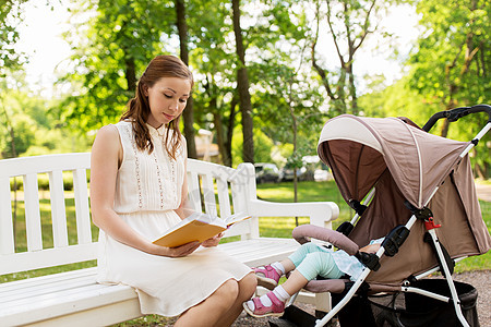 家庭,母亲人的快乐的母亲与孩子婴儿车阅读书夏季公园母亲带着孩子婴儿车公园读书图片