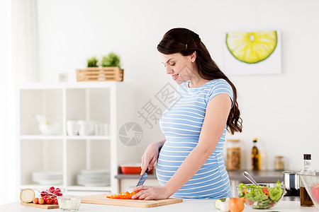 健康饮食,怀孕,食物人的孕妇烹饪蔬菜沙拉切胡椒粉家厨房孕妇家煮蔬菜沙拉图片