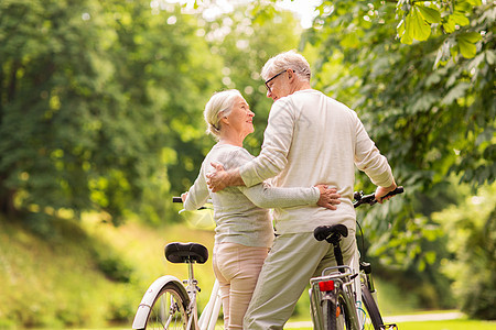 老,人生活方式的快乐的老夫妇与自行车拥抱夏季城市公园快乐的老夫妇夏季公园骑自行车图片