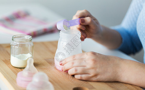 食物营养母亲手与婴儿瓶铲子准备婴儿配方奶用瓶子勺子制作配方牛奶图片