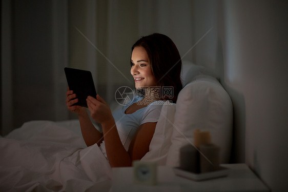 技术,互联网,沟通人的快乐的微笑轻妇女与平板电脑电脑床上家里的卧室晚上轻的女人家里卧室的床上平板电脑图片