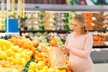 销售,购物,食物,怀孕人们的快乐的孕妇购买橘子,并将它们放入纸袋杂货店超市孕妇带着袋子杂货店买橘子图片
