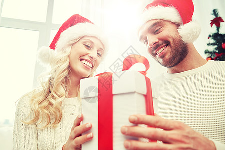 诞节,假日人们的幸福的夫妇戴着诞老人的帽子,礼品盒坐家里的沙发上幸福的夫妇家带着诞礼盒图片