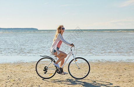 人们,休闲生活方式的快乐的轻女人骑自行车沿夏海滩快乐的女人沿着夏天的海滩骑自行车图片