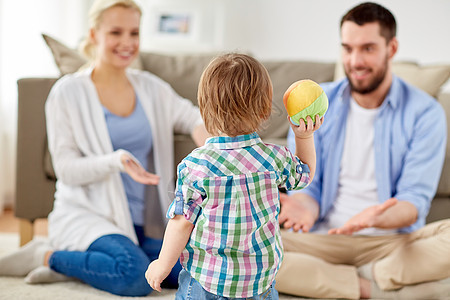 家庭人的快乐的小儿子父母家玩球快乐的家庭家里玩球图片