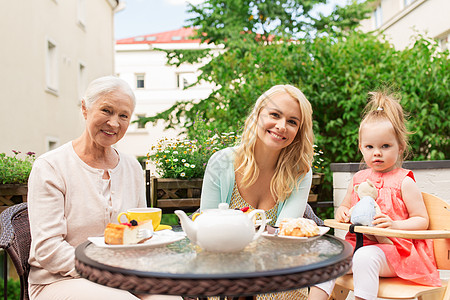 家庭,世代人的快乐的微笑母亲,祖母孙女咖啡馆餐厅露台咖啡馆的母亲祖母孙女图片