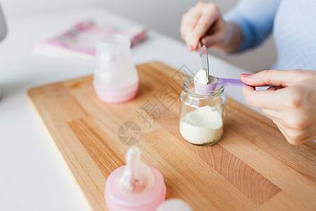 食物营养母亲手与铲子,罐子婴儿瓶准备婴儿配方奶用罐子铲子制作配方奶图片