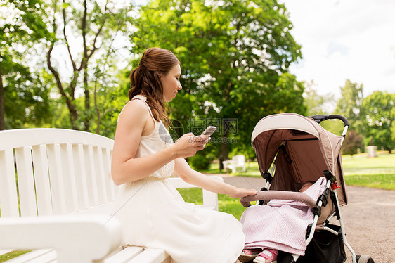 母亲,技术人的快乐的母亲与智能手机女婴婴儿车夏季公园快乐的母亲公园用智能手机婴儿车图片