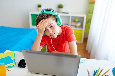 技术,游戏,网络欺凌人的心烦意乱的男孩耳机与笔记本电脑家里失电子游戏遭受欺凌戴耳机的男孩笔记本电脑上玩电子图片