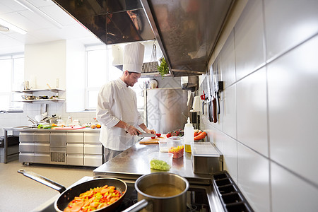 烹饪食物,职业人的男厨师用刀切西红柿餐厅厨房的砧板上饭餐厅厨房的男厨师烹饪食物图片