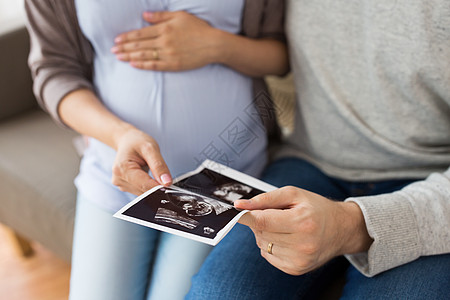 怀孕,家庭人的密切的男人他怀孕的妻子家里看婴儿超声图像夫妇与婴儿超声图像图片