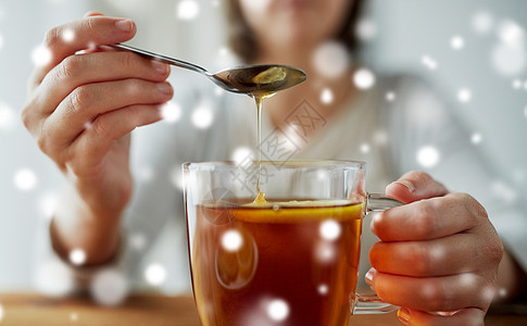 健康食品,饮食民族科学的密切妇女添加蜂蜜茶杯与柠檬雪特写女人用柠檬茶中加入蜂蜜图片