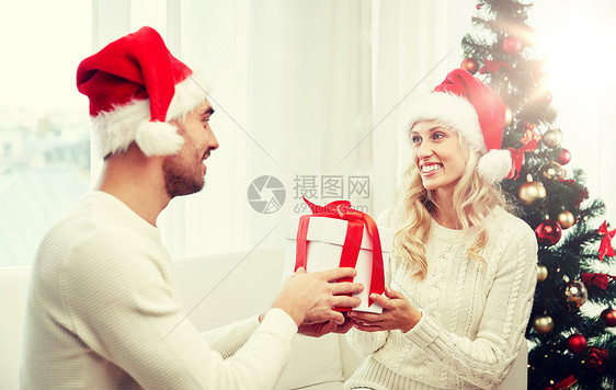 诞节,假日人们的幸福的夫妇戴着诞老人的帽子,礼品盒坐家里的沙发上幸福的夫妇家带着诞礼盒图片