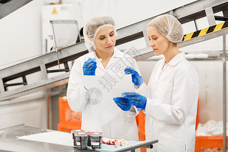 食品生产,工业人的妇女技术人员与剪贴板品尝冰淇淋质量工厂女技术人员工厂品尝冰淇淋图片