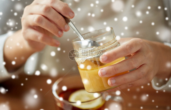 健康,传统医学民族科学的密切妇女添加蜂蜜茶与柠檬雪特写女人用柠檬茶中加入蜂蜜图片