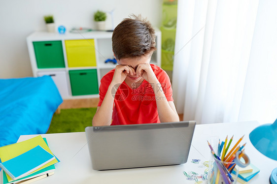 教育网络欺凌技术人的疲惫哭泣的学生男孩家里用笔记本电脑摩擦眼睛遭受欺凌疲惫的学生男孩家着笔记本电脑图片