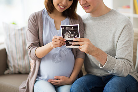 怀孕,家庭人的接近快乐的男人与他怀孕的妻子家里看婴儿超声图像夫妇与婴儿超声图像家里图片