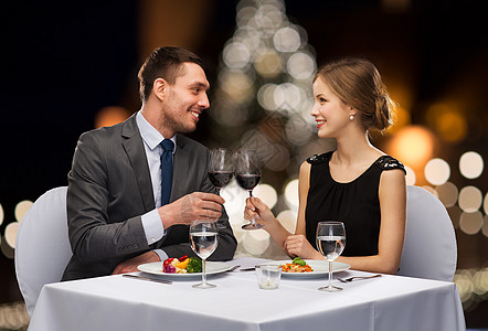 庆祝,人节日的微笑的夫妇诞树下的餐厅碰杯非酒精葡萄酒诞节含酒精的酒图片