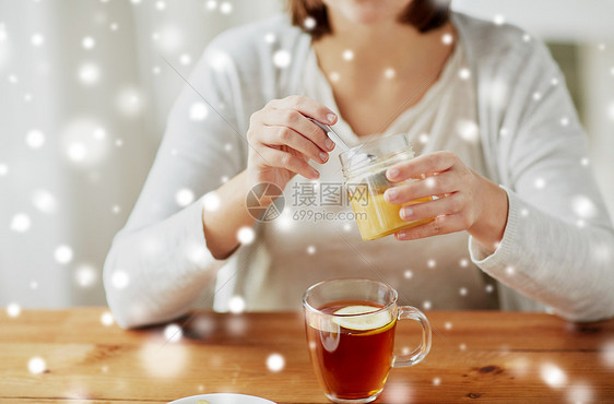 健康,传统医学民族科学的密切妇女添加蜂蜜茶与柠檬雪特写女人用柠檬茶中加入蜂蜜图片