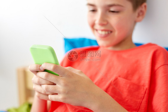 童,技术沟通亲密的快乐微笑男孩与智能手机家里家用智能手机快乐男孩图片