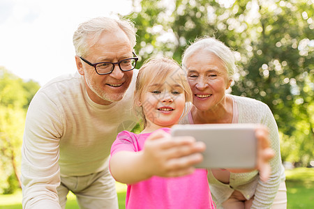 快乐的祖父母孙女公园用智能手机自拍图片