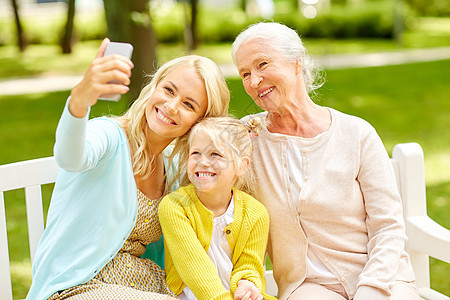 家庭世代人的快乐的微笑母亲与女儿祖母公园用智能手机自拍母亲带着女儿祖母公园图片