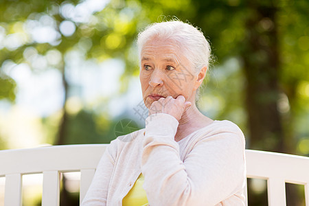 老退休人们的观念悲伤的老妇女坐夏季公园的长凳上悲伤的高级女人坐夏天公园的长凳上图片