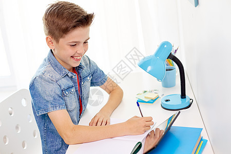 教育,童人的快乐的学生男孩与平板电脑写笔记本家里学生男孩用平板电脑写笔记本图片