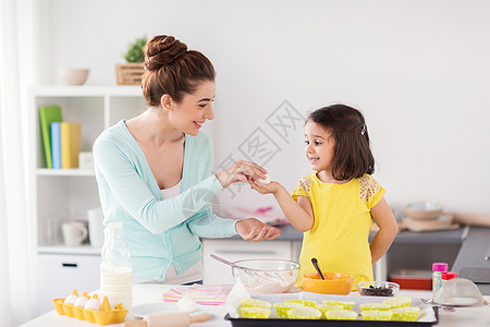 端着烤家庭,烹饪,烘焙人们的快乐的母亲小女儿着鸡蛋,家里的厨房纸杯蛋糕快乐的母女家烘焙背景