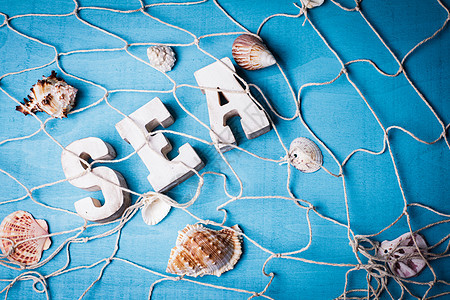 美丽的海洋构图,木制字母蓝色背景上的渔网海洋内部装饰图片