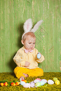 小男孩像复活节兔子样草地上放着五颜六色的鸡蛋复活节兔子蹒跚学步图片