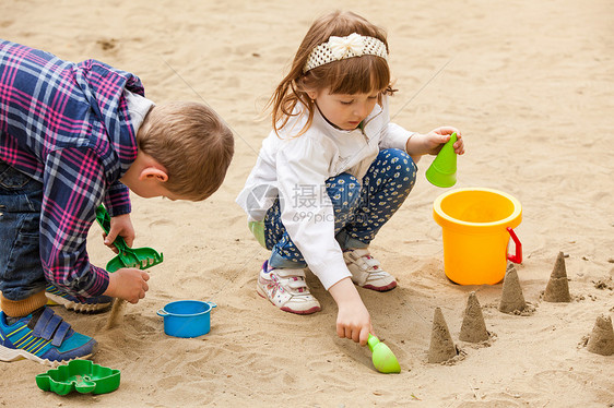 女孩男孩沙箱里用沙子建造人物孩子们沙箱里玩图片