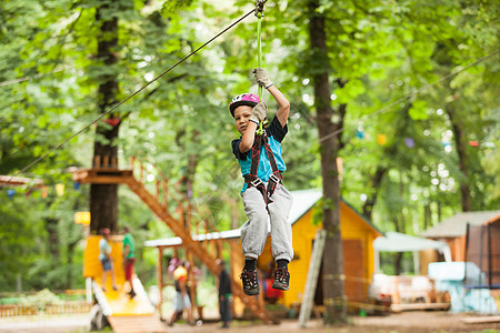 个男孩戴着头盔安全设备冒险绳索公园的自然背景孩子冒险游乐场图片