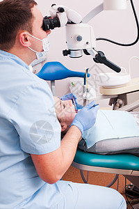 牙医透过放大镜看他牙科办公室用显微镜手术图片