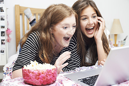 两个十几岁的女孩卧室里用笔记本电脑看电影图片