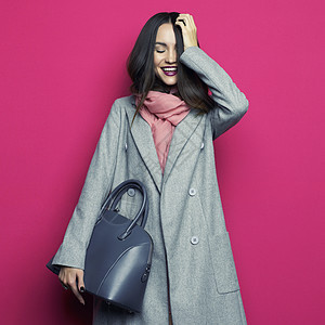 时尚工作室照片轻时尚的女人紫红色背景灰色外套,粉红色围巾,紫色口红,皮包,目录衣服配件看书图片