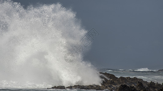 股东来了股巨大的波浪风暴河口的海岸线上撞击岩石,造成了巨大的飞溅背景