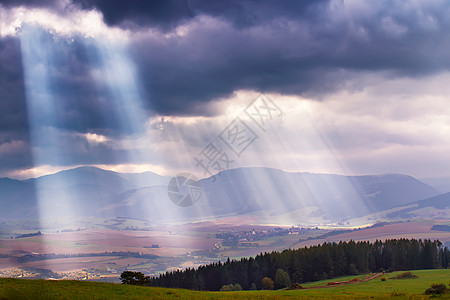 阳光透过云层阳光照耀Tatra山的云层上多云天空中的光线背景